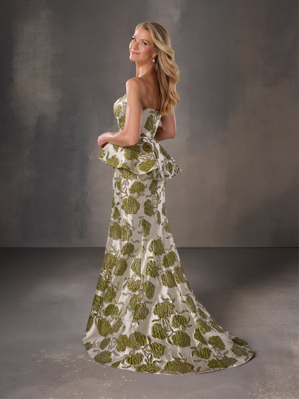 Woman wearing a strapless green and white floral dress against a gray background / Strapless floral brocade peplum fit & flare gown.