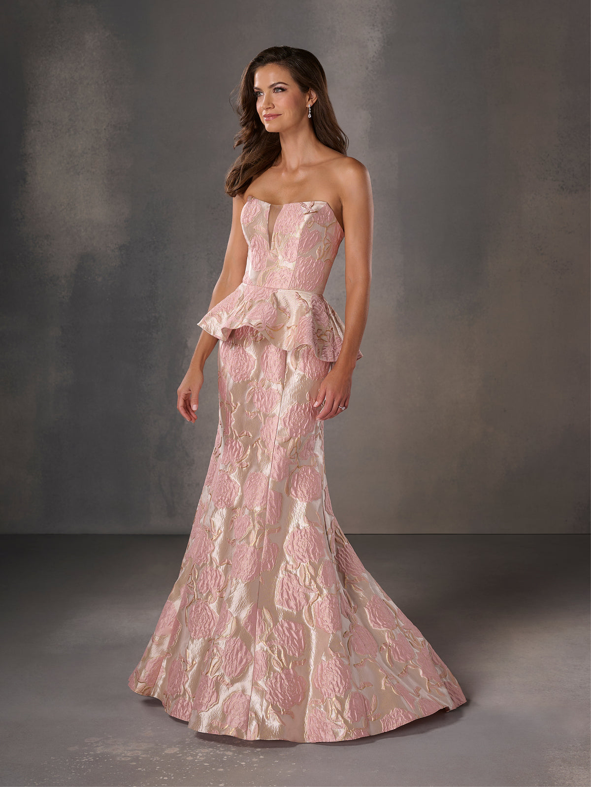 Woman wearing a pink strapless gown with ruffled layers against a gray background / Strapless floral brocade peplum fit & flare gown.
