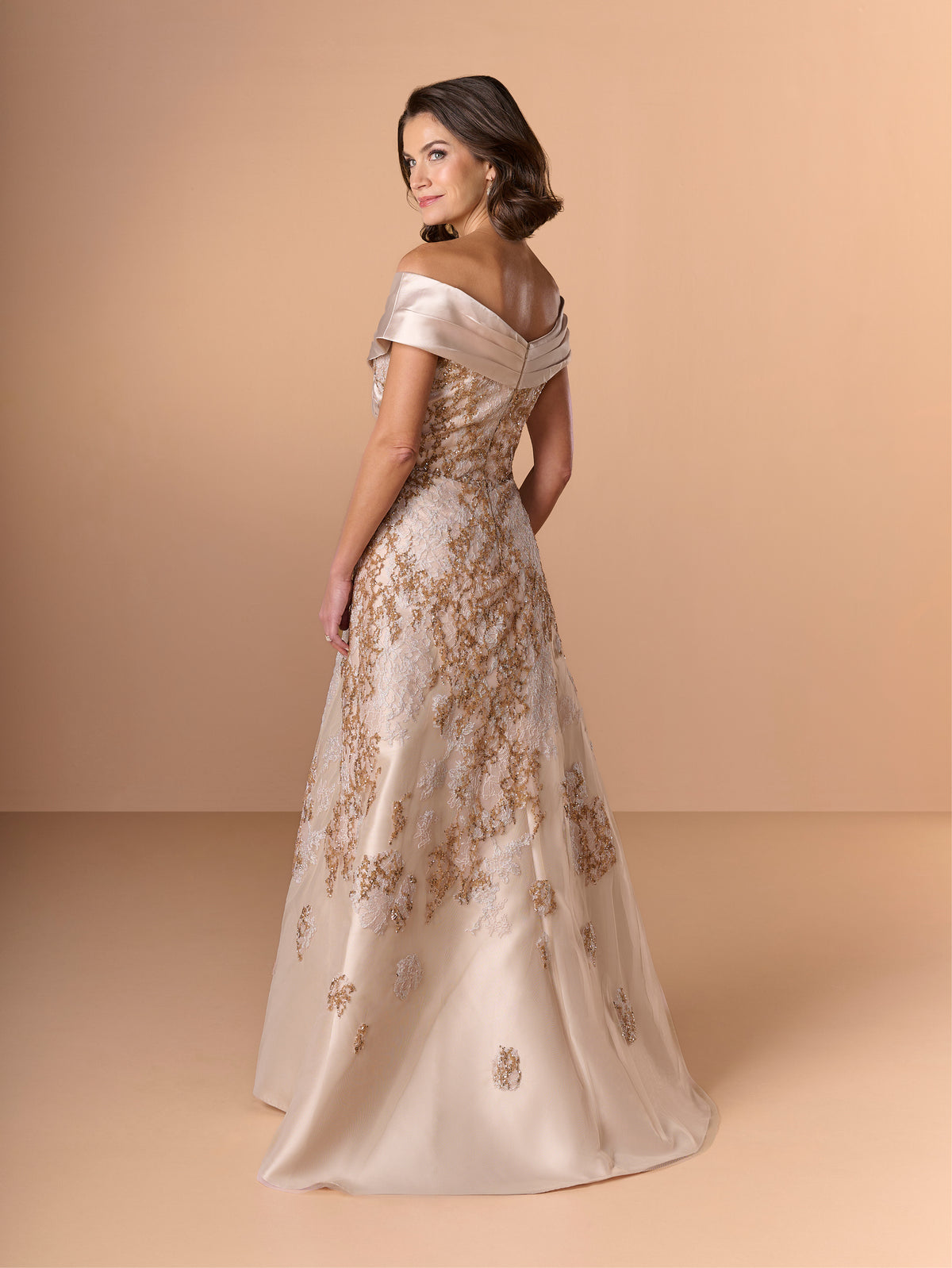 Woman wearing an off-shoulder evening gown with floral embroidery on a beige background / A-line lace dress with mikado collar off-shoulder.