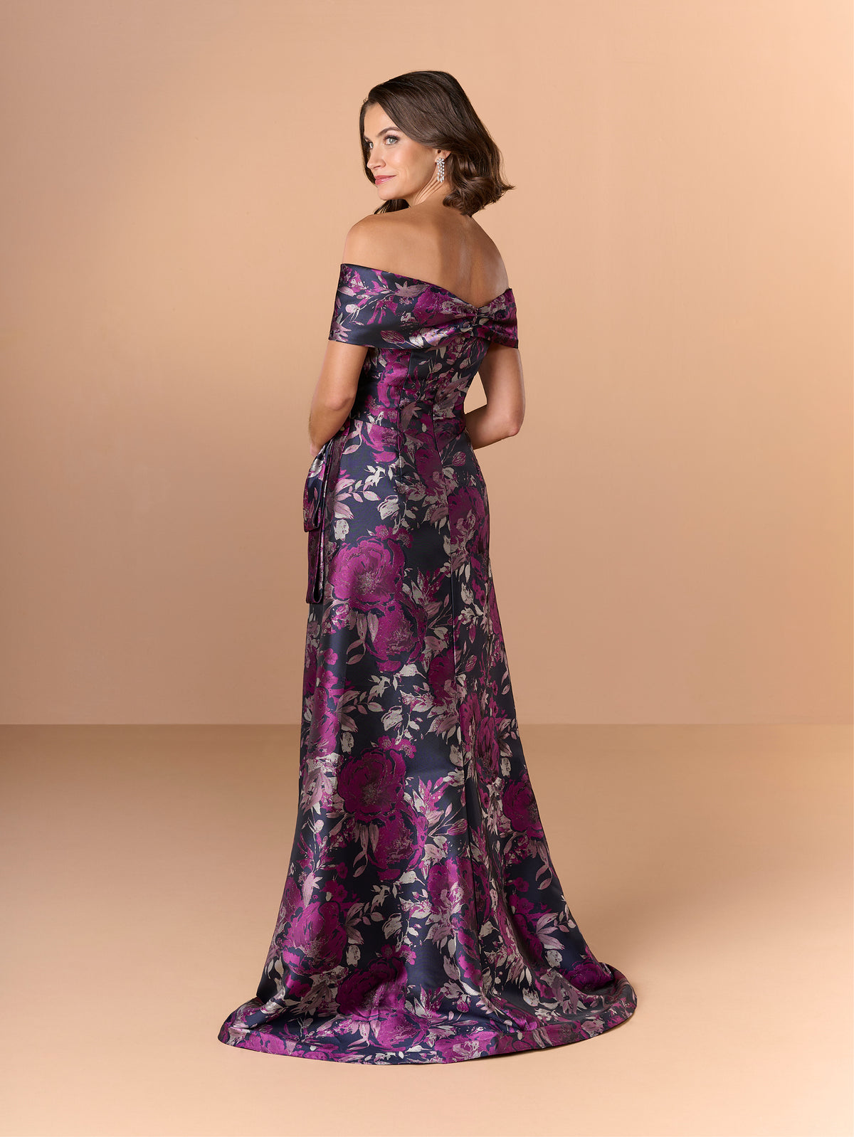 Woman wearing a floral off-shoulder gown on a beige background / Slim brocade style with collar/straps twist, pleating on front bodice.