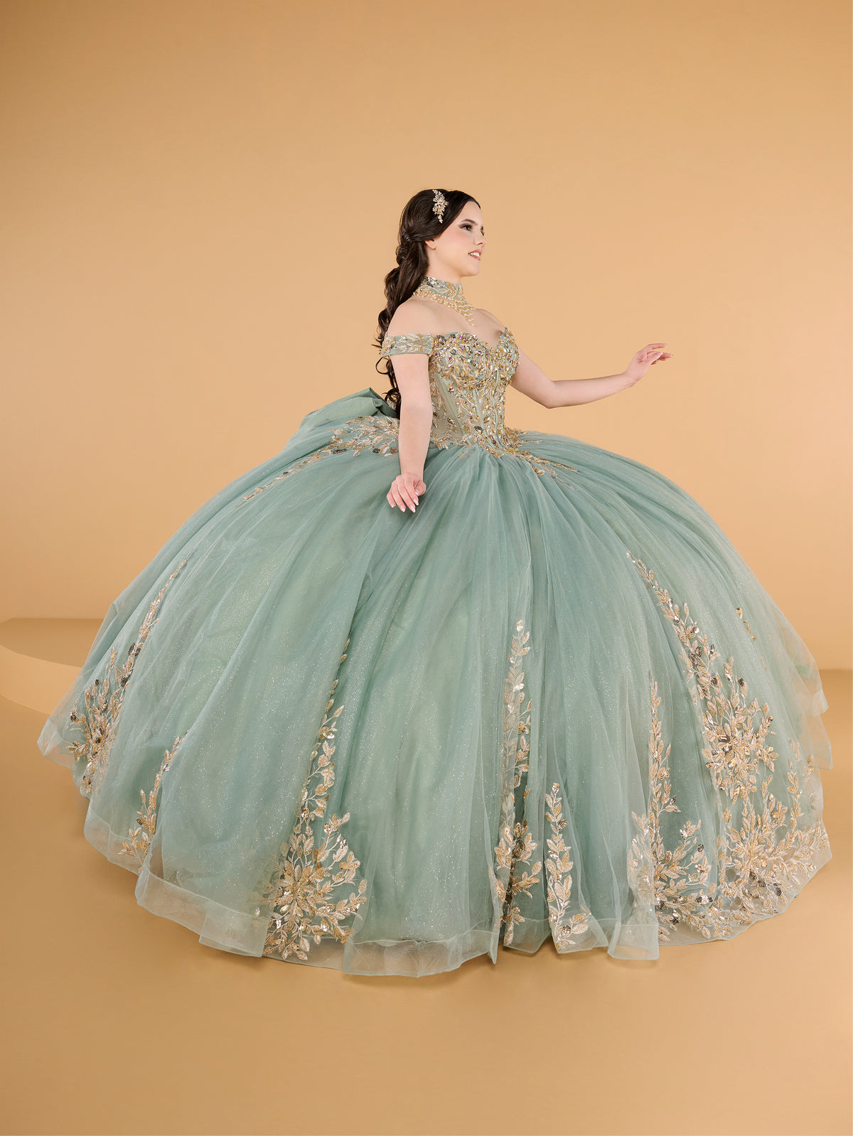This ball gown features an ornate bodice with detailed embroidery and off-the-shoulder straps. The full tulle skirt is embellished with matching floral designs and finished with a dramatic bow and sweeping train.