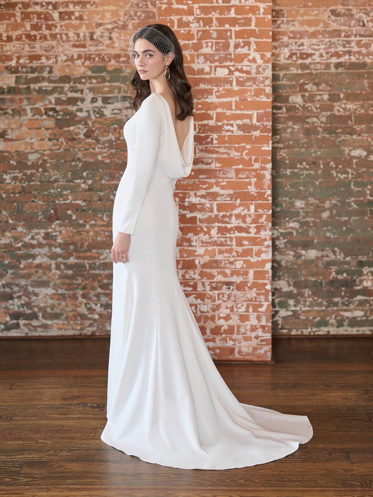 This stretch crepe gown features a high neckline with long sleeves and a low cowl back. The fitted skirt has a slit at the front.