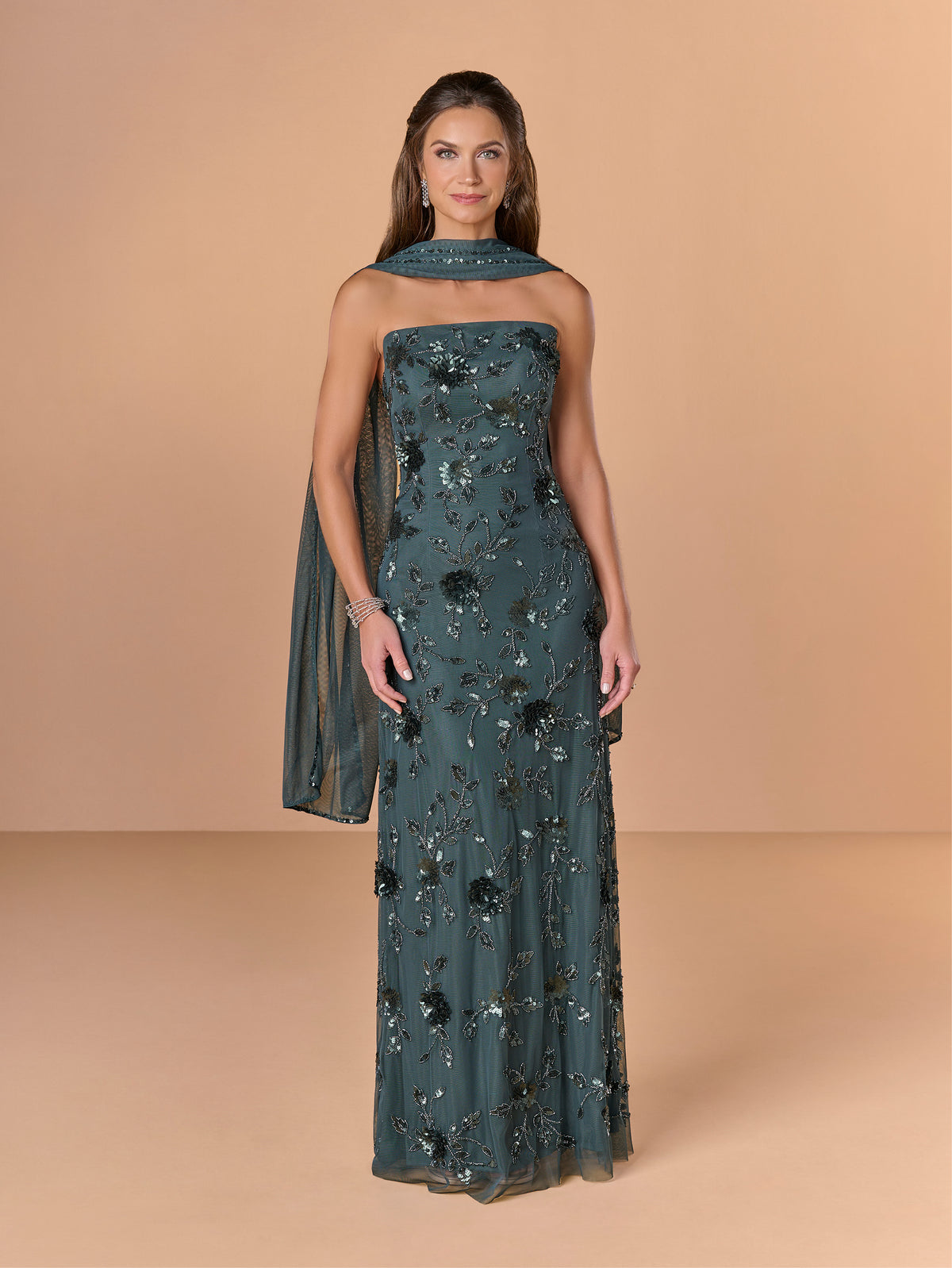 Woman wearing a dark green strapless gown with floral patterns on a beige background / All over beaded gown with high straight neckline, 3D flowers and matching separate shawl.