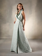 Woman wearing a light green evening gown with a textured pattern against a neutral background / Sleeveless floral jacquard A-line with high ruffled collar.