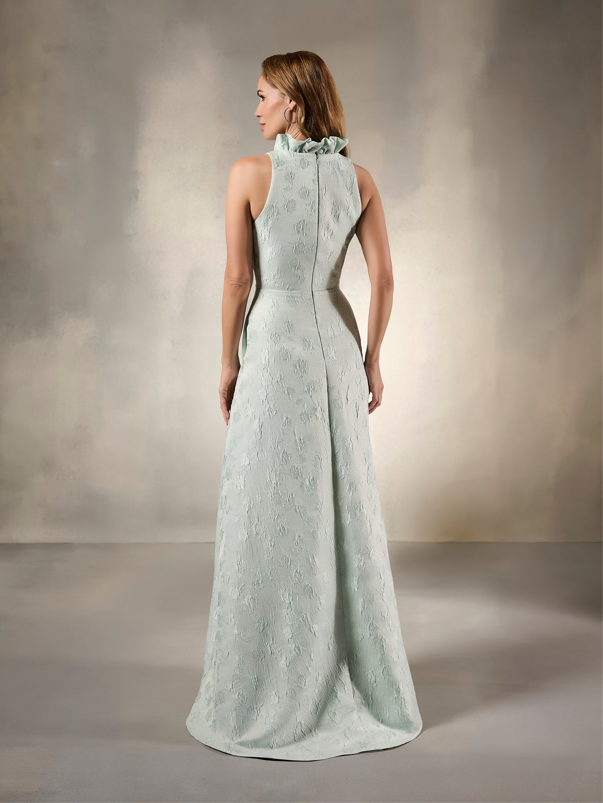 Woman wearing a light blue evening gown against a neutral background / Sleeveless floral jacquard A-line with high ruffled collar.