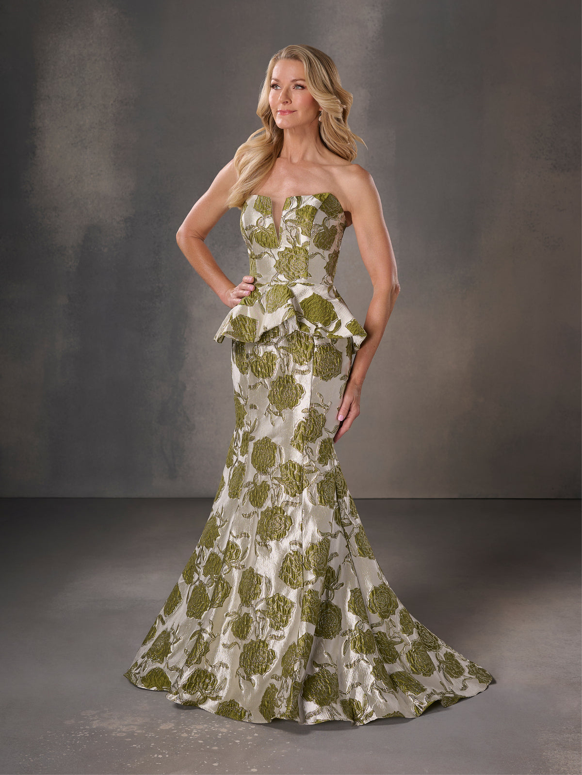 Woman wearing a strapless green and white patterned gown against a gray background / Strapless floral brocade peplum fit & flare gown.