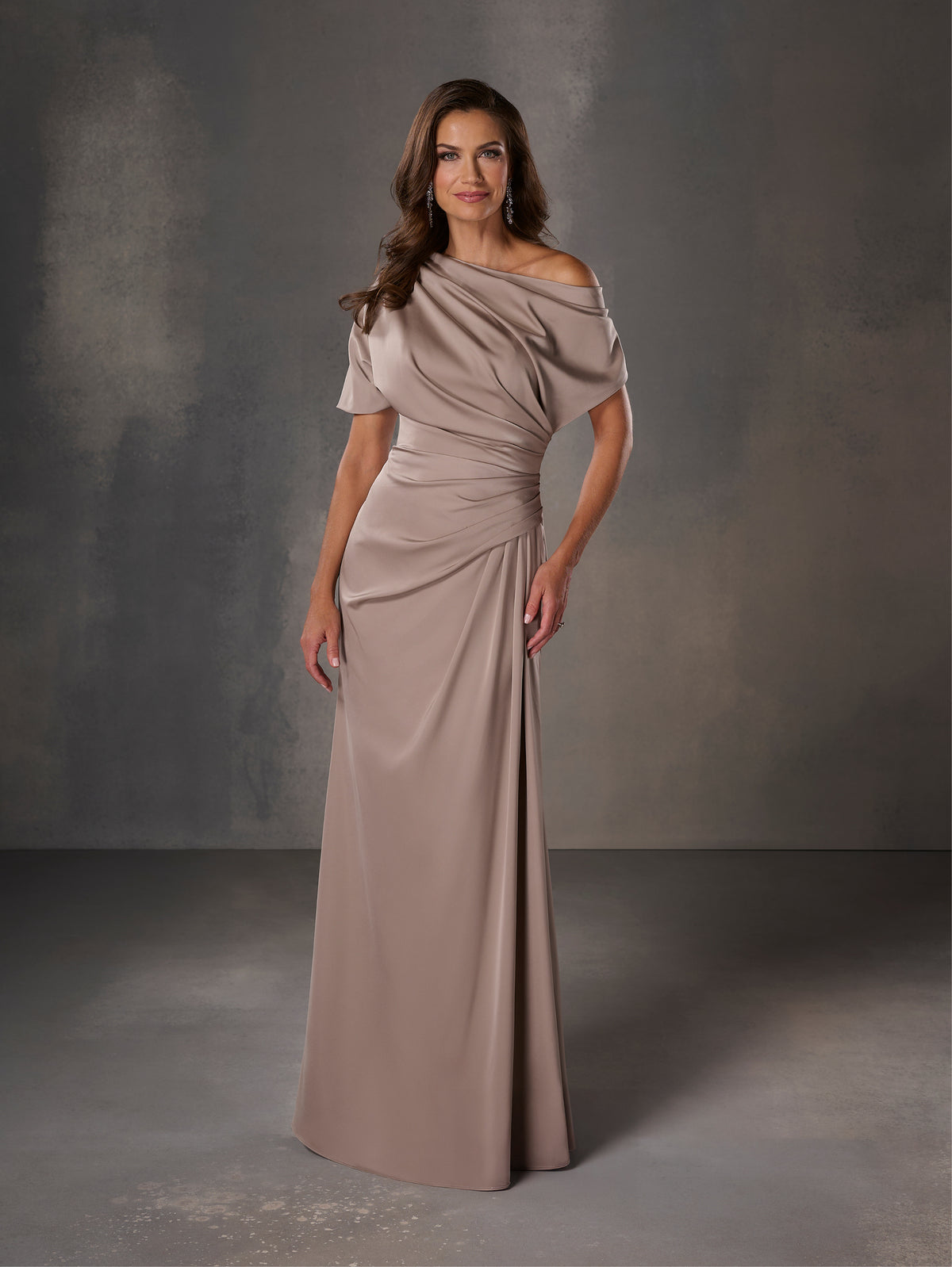 Woman wearing a long, off-shoulder dress against a gray background / Stretch charmeuse slim A-line with asymmetrical neckline and off-shoulder sleeve on one side.