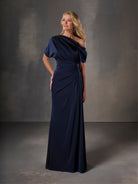 Woman wearing a navy blue evening gown against a gray background / Stretch charmeuse slim A-line with asymmetrical neckline and off-shoulder sleeve on one side.