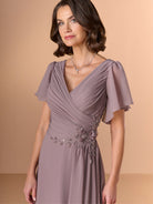 Woman wearing a mauve evening gown with floral embellishments on a beige background / A-line chiffon style with V-neck and short flatter sleeves. Finely gathering on bodice finished with hand beading motif on side waist area.