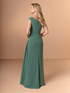 Woman wearing a green evening gown against a beige background / Slim crepe style with V-neck and cup shoulder. Side pleating on front dress with long ruffle on side.