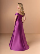 Woman wearing a purple off-shoulder gown against a beige background / A-line mikado style with sweetheart neckline and off-shoulder straps, front draping with bow feature on side.