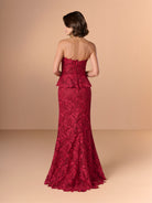 Woman wearing a red lace evening gown against a beige background / Created with a truly exquisite lace, this strapless gown features a figure-flattering peplum with a stand-away organically cut neckline.