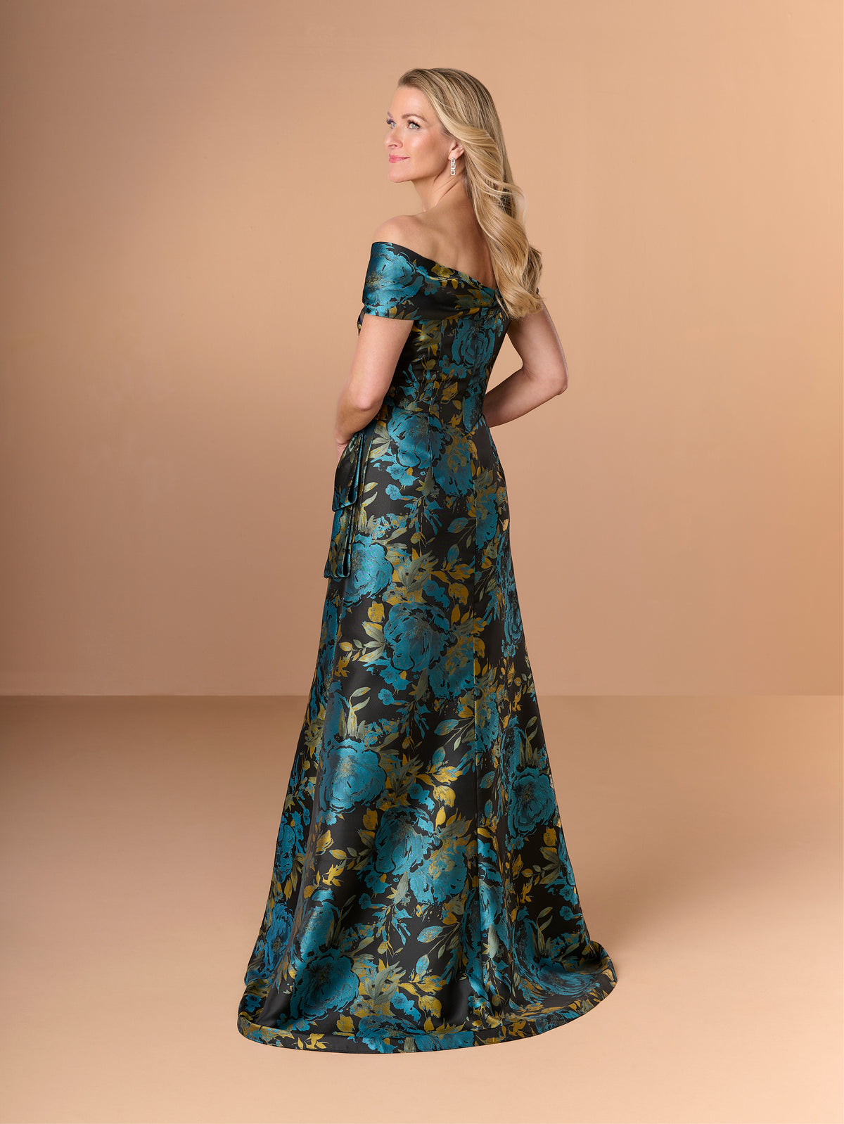 Woman wearing a floral off-shoulder gown against a beige background / Slim brocade style with collar/straps twist, pleating on front bodice.