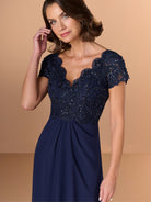 Woman wearing a navy blue dress with lace detailing on a beige background / A-line style with lace bodice and chiffon skirt. V-neck edge and short sleeves hemline edge finished with scallops. Draping on front and back skirt in fan shape.