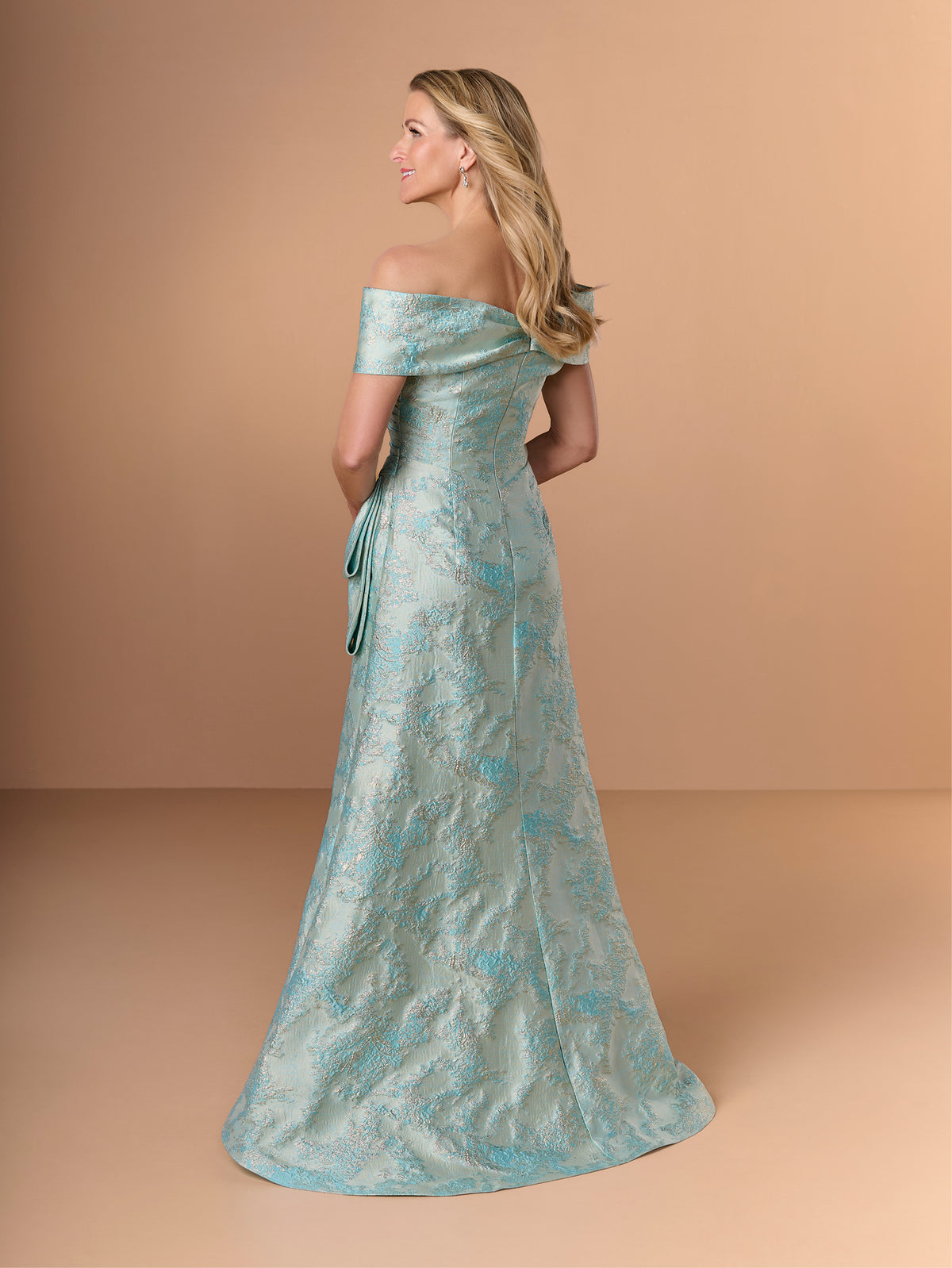 A woman modeling an off-the-shoulder floor-length gown in a light aqua blue and white jacquard pattern, photographed against a solid warm beige studio backdrop. / Slim jacquard style with collar/straps twist, pleating on front bodice.
