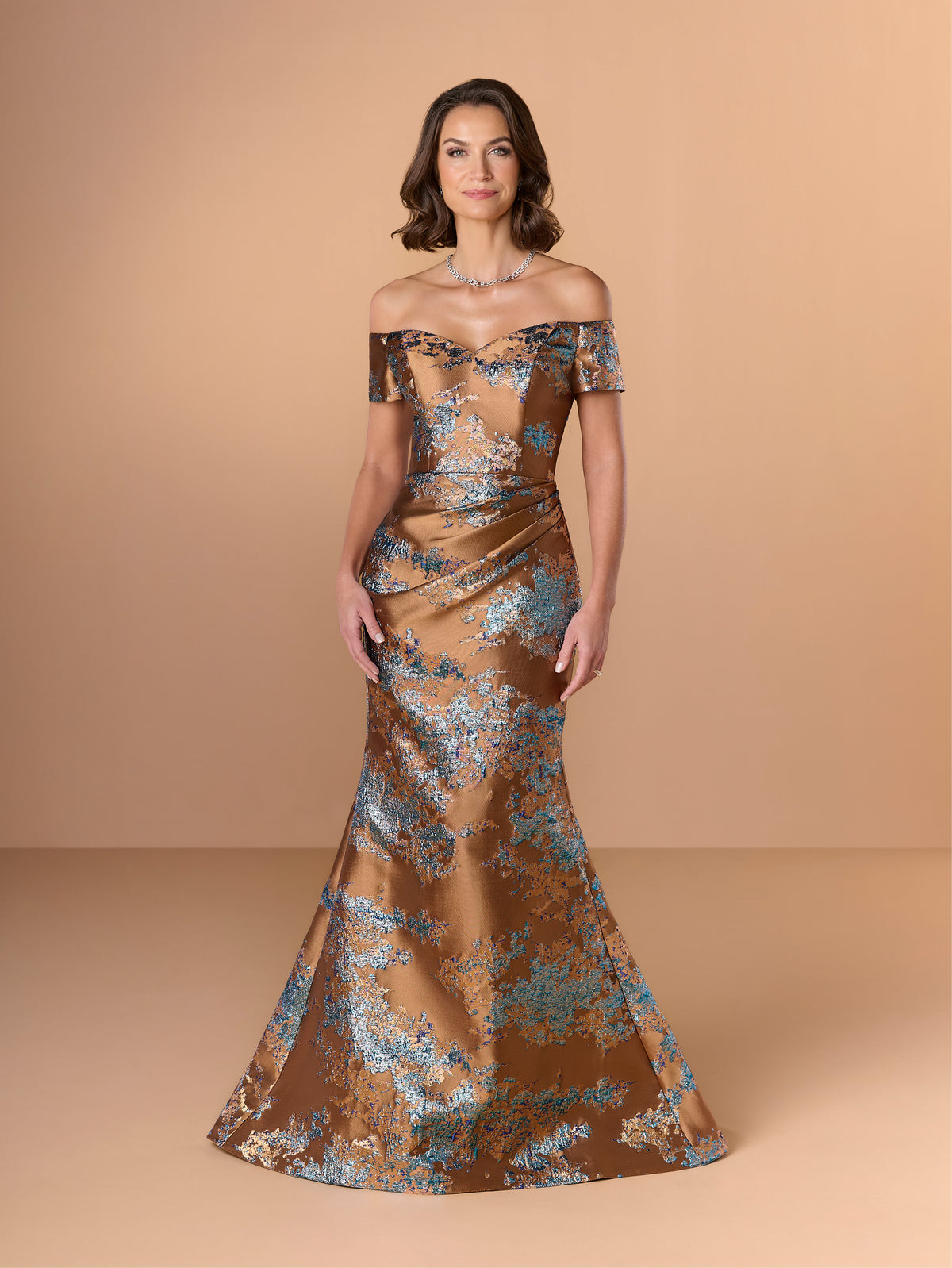 Woman wearing a bronze off-shoulder gown with floral patterns on a beige background / Slim brocade style with sweet off-shoulder neckline, short sleeves, draping on stomach area.