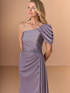 Woman wearing a one-shoulder purple gown with an embellished waistband against a beige background / Slim style in stretch charmeuse with asymmetrical neckline draped with detachable collar. Side draping on bodice finished with beaded motif on waist area.