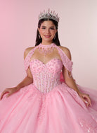 A woman wearing an ornate pink ball gown with a corset-style bodice, cold-shoulder lace sleeves, and a full tulle skirt, posed against a soft pink studio background. She is also wearing a jeweled tiara and dangling earrings. / Elegant ball gown featuring a beaded off-shoulder bodice, cascading ruffle details, intricate embellishments, and a dramatic oversized bow with a sweeping train.