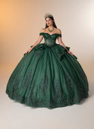 A woman wearing a voluminous off-the-shoulder emerald green ball gown with intricate beadwork and a matching tiara, posing against a warm beige studio background. / Luxurious off-shoulder ball gown featuring glittering embellishments, layered draped skirt details, and a dramatic cathedral-length train for a breathtaking princess-inspired look.