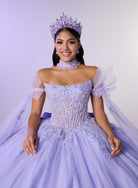 A woman wearing an elaborate lavender quinceañera-style ball gown with a jeweled corset bodice, sheer puff sleeves, a matching veil, tiara, and pearl choker, posed against a pale lavender studio background. / Dreamy off-shoulder ball gown featuring delicate sparkling appliqués, a structured corset bodice, a voluminous tulle skirt, and an oversized statement bow at the back.