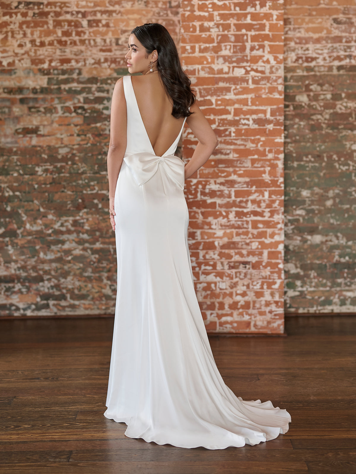 This stretch matte charmeuse gown has a chic, bateau neckline and slim skirt. The back features a plunging, low v and a simple bow.