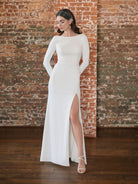 This stretch crepe gown features a high neckline with long sleeves and a low cowl back. The fitted skirt has a slit at the front.