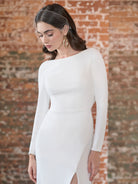 This stretch crepe gown features a high neckline with long sleeves and a low cowl back. The fitted skirt has a slit at the front.