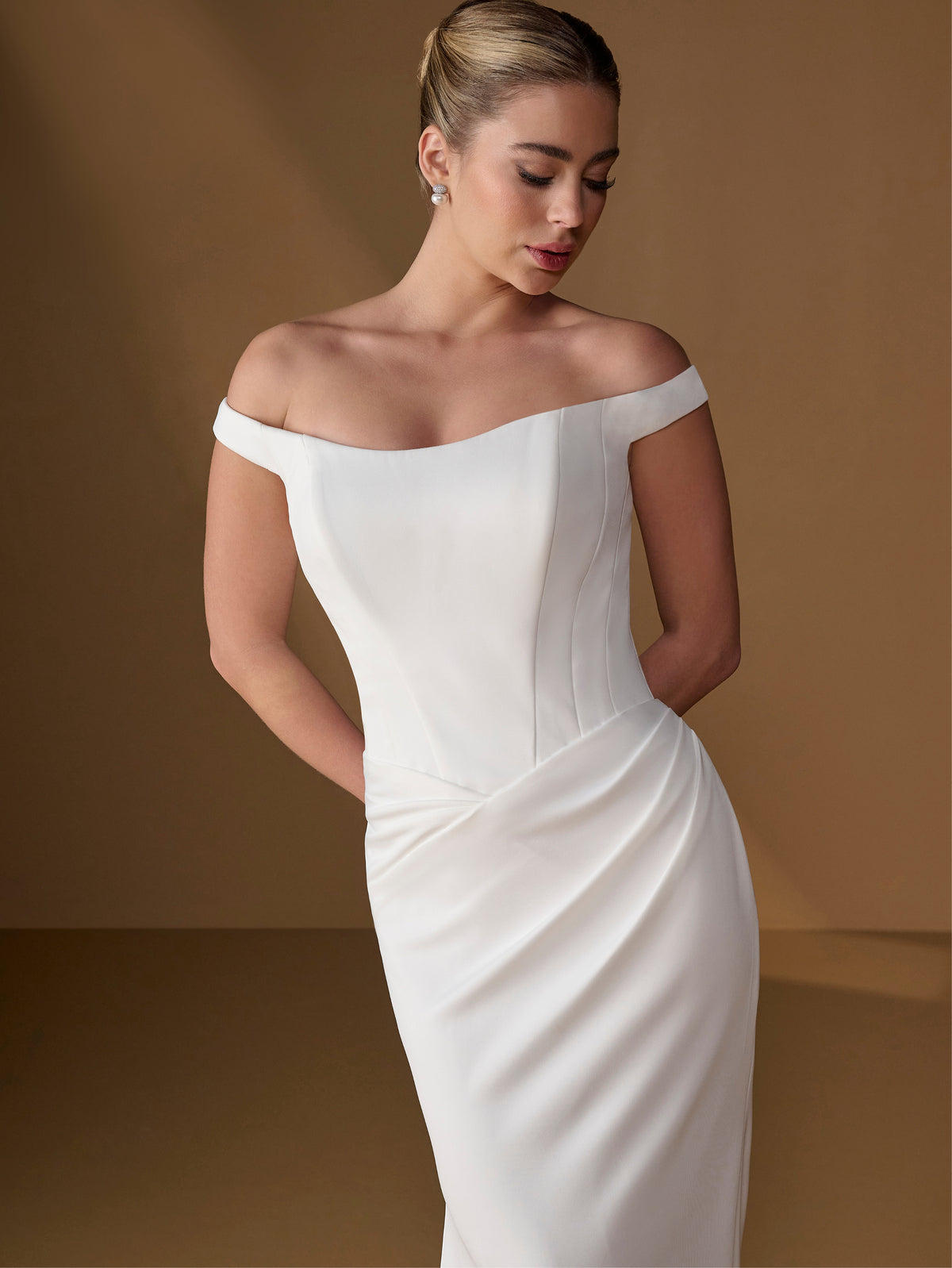 Woman wearing a white off-shoulder gown against a brown background / Tip of the shoulder gown with v waist and lace up back.