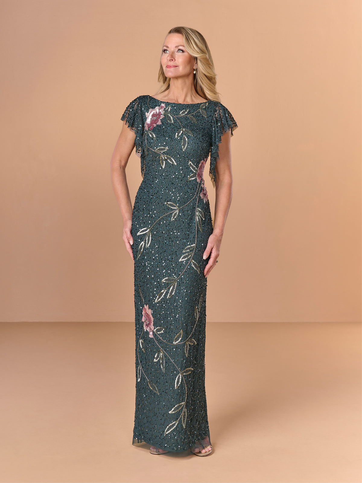 Woman wearing a floral dress with a beige background / All over beaded column gown with flutter sleeve and back cowl.