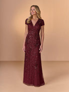 Woman wearing a burgundy sequin dress against a beige background / All over beaded gown with v neckline and cap sleeve.