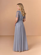Woman wearing a long, light blue lace dress against a beige background / Beaded bodice with v neckline, short sleeve and solid A-line skirt.