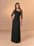 A woman modeling a floor-length black evening gown with sheer three-quarter sleeves and a draped neckline, standing against a warm beige studio backdrop. / All over beaded gown with asymmetrical neckline and body shirring.