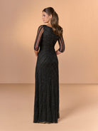 A woman modeling a floor-length black evening gown from the back, featuring sheer three-quarter sleeves and intricate beaded detailing, set against a solid beige studio backdrop. / All over beaded gown with asymmetrical neckline and body shirring.
