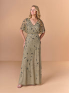 Woman wearing a long, patterned dress against a beige background / All over beaded gown with surplice, blouson bodice and soft A-line skirt.