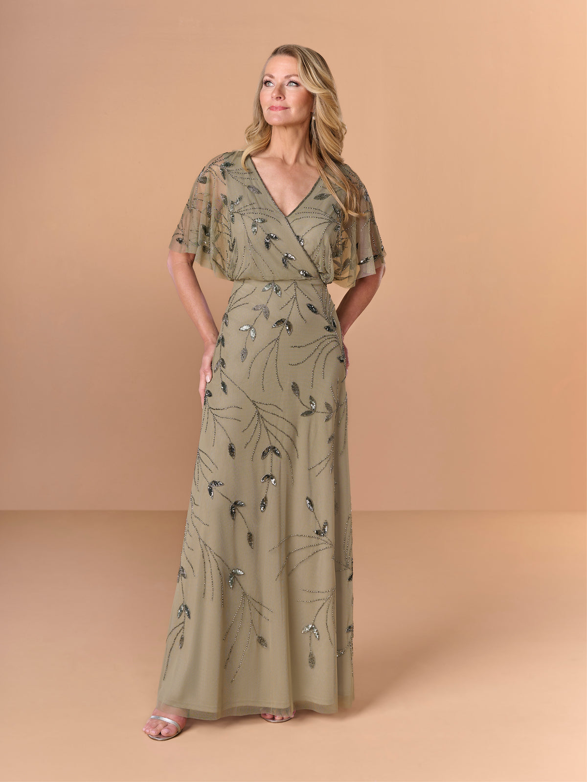 Woman wearing a long, patterned dress against a beige background / All over beaded gown with surplice, blouson bodice and soft A-line skirt.