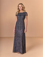 Woman wearing a dark lace evening gown against a beige background / All over beaded gown with scoop neck and short sleeve.