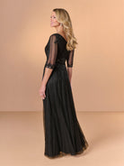 Woman wearing a black lace dress against a beige background / All over beaded gown with surplice bodice, elbow length sleeve and full A-line skirt.