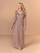 Woman wearing a long, sparkly, rose gold dress against a beige background / All over crunchy bead gown with long sleeves and cowl back.