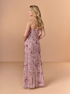 Woman wearing a floral strapless gown against a beige background / All over beaded gown with high straight neckline, 3D flowers and matching separate shawl.