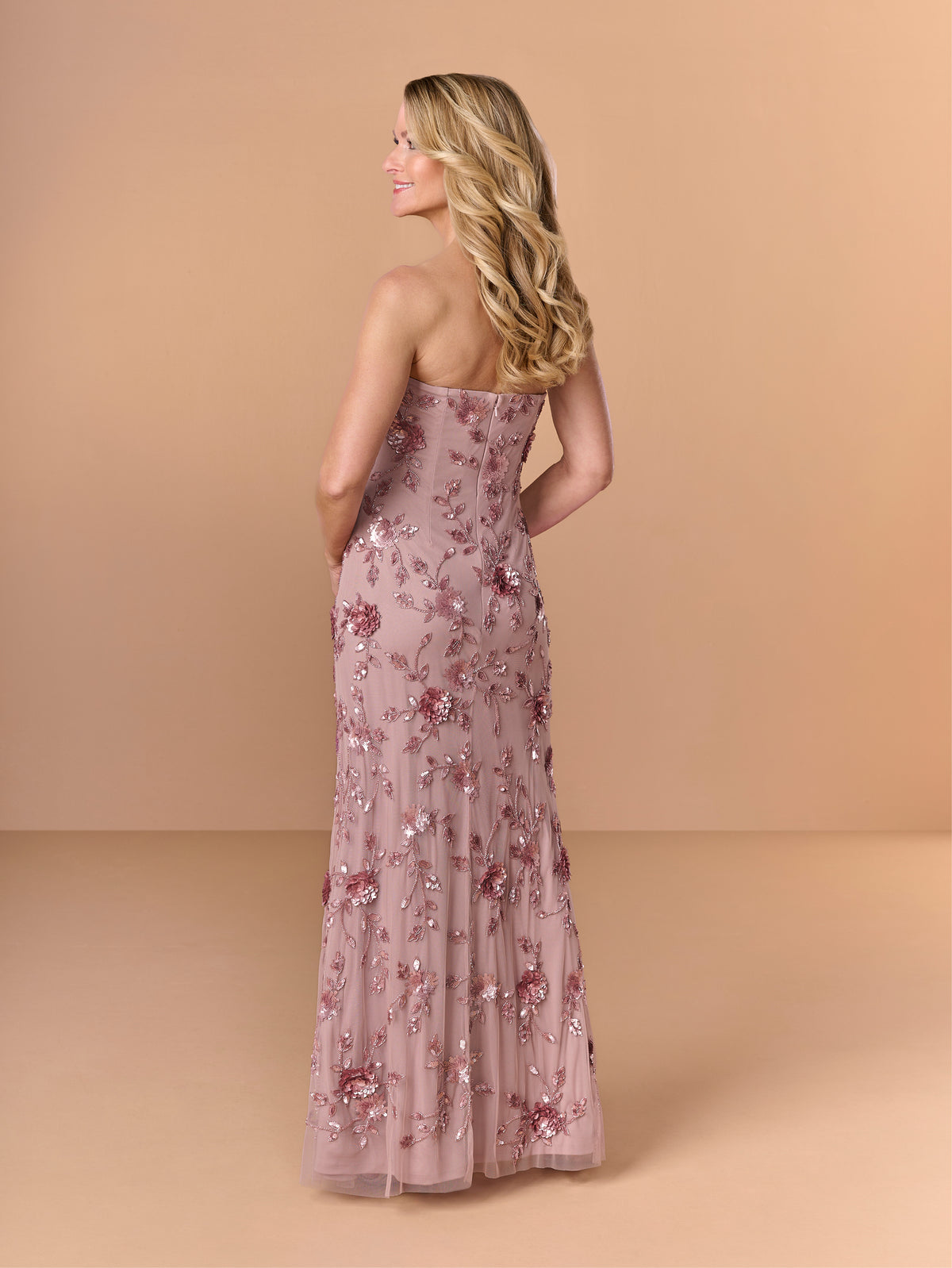 Woman wearing a floral strapless gown against a beige background / All over beaded gown with high straight neckline, 3D flowers and matching separate shawl.