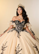 A woman wearing a voluminous off-the-shoulder quinceañera dress with a black lace corset bodice and beige tulle skirt with black floral embroidery, accessorized with a gold crown and necklace, posed against a warm beige studio background. / A strapless ball gown with a lace-up bodice and a voluminous tulle skirt featuring floral embroidery and a large back bow.