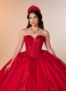 A young woman modeling a bright red strapless ball gown with a sweetheart neckline, heavily embellished with sequins and beadwork, paired with a matching red tiara and necklace against a warm beige studio background. / A strapless ball gown featuring a beaded corset bodice, a voluminous glitter-tulle skirt with sequin appliques, and a textured ruffle accent on the back.