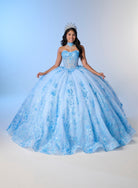 A young woman modeling a voluminous light blue quinceañera ball gown with floral lace applique, a sweetheart neckline, and a matching tiara against a soft blue studio backdrop. / A strapless sweetheart ball gown featuring a fully beaded corset bodice, a lace-up back, and a voluminous tulle skirt layered with shimmering sequin floral details and an oversized back bow, paired with a matching beaded choker necklace.