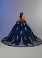 A woman wearing a voluminous off-the-shoulder ball gown from behind, showcasing a deep navy blue tulle skirt adorned with intricate gold floral embroidery and a matching long train against a studio backdrop. / Two-piece off-shoulder dress with a fitted, embellished bodice and a short, form-fitting skirt, featuring a sweetheart neckline, sparkling embroidered details, detachable arm drapes, and a full tulle skirt with a sweeping train.