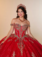 A young woman modeling a red off-the-shoulder ball gown with extensive gold embroidery, wearing a matching red and gold tiara and necklace against a solid beige background. / Elegant off-shoulder ball gown featuring intricate embroidered detailing, a structured bodice, and a voluminous skirt with a dramatic statement bow at the back.