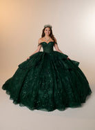 A young woman wearing a voluminous dark green off-the-shoulder ball gown with a tiara, standing against a plain beige studio background. / Glamorous ball gown featuring a sparkling embellished corset bodice, dramatic layered overskirt details, a voluminous skirt, and an elegant sweeping train.