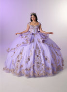 A woman wearing a voluminous lavender quinceañera ball gown with gold floral embroidery and a tiara, posed against a light lavender studio backdrop. / Regal ball gown featuring intricate embroidered appliqués, a structured bodice, dramatic layered overskirt details, and a sweeping cathedral-length train for a royal-inspired look.